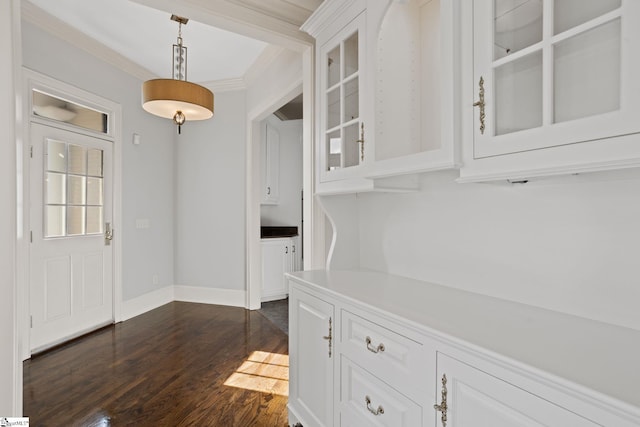 interior space with baseboards, dark wood-style floors, and ornamental molding