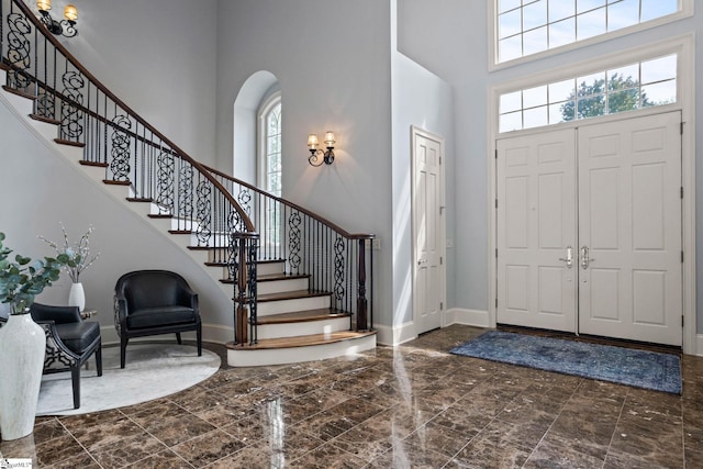 entrance foyer featuring baseboards, stairs, a high ceiling, and a healthy amount of sunlight