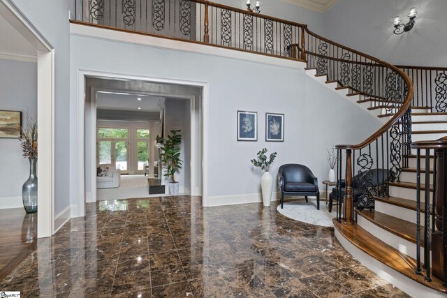 entryway with baseboards, marble finish floor, a towering ceiling, stairs, and ornamental molding