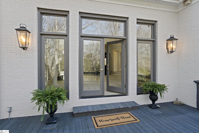 property entrance with a wooden deck and brick siding