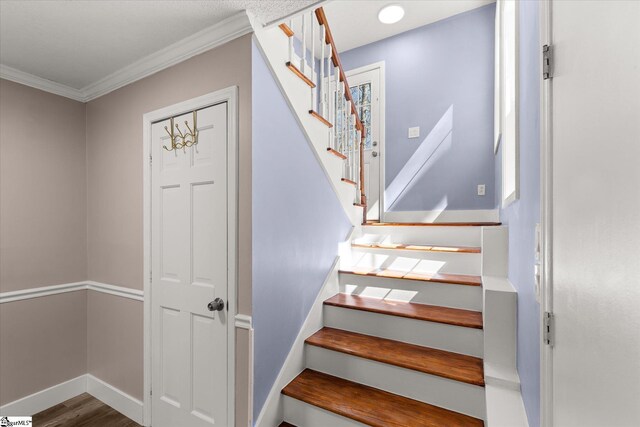 staircase featuring ornamental molding, baseboards, and wood finished floors