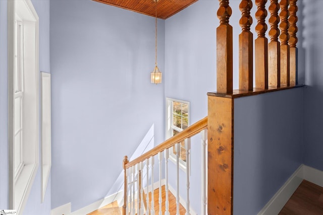 stairway with baseboards, wood finished floors, and wooden ceiling
