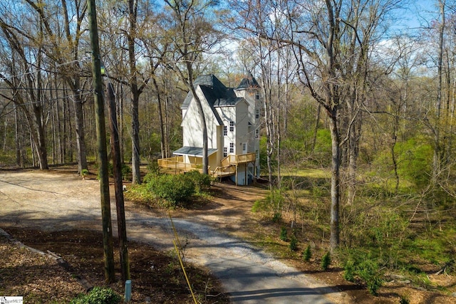 view of home's exterior featuring driveway and a wooded view