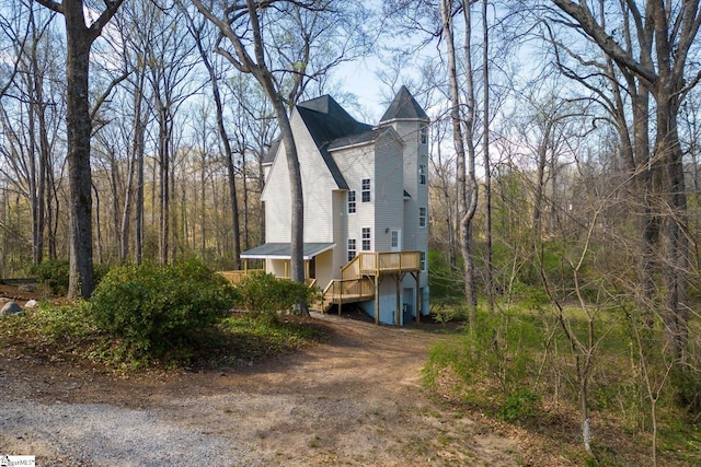view of side of property with dirt driveway and a deck