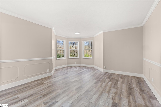 unfurnished room featuring light wood-style flooring, a decorative wall, and ornamental molding