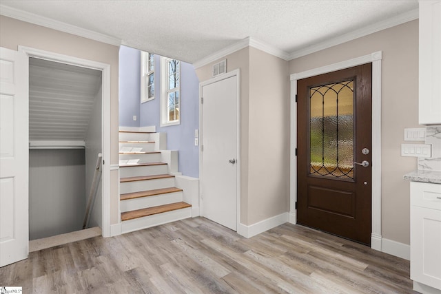 foyer entrance with ornamental molding, visible vents, stairway, and light wood-type flooring