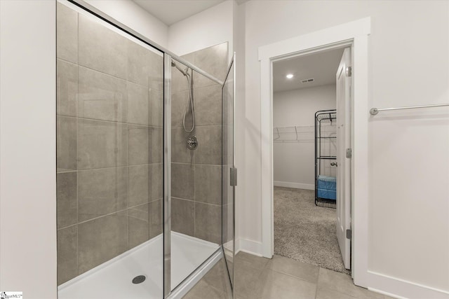 bathroom featuring a stall shower, a walk in closet, tile patterned flooring, baseboards, and visible vents