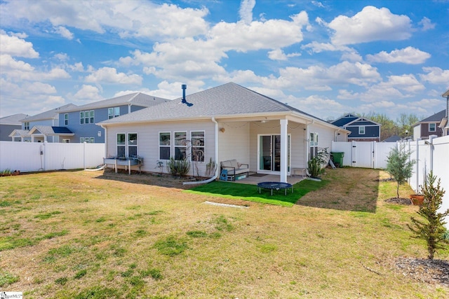 rear view of property with a lawn, a fenced backyard, a trampoline, a gate, and a patio area