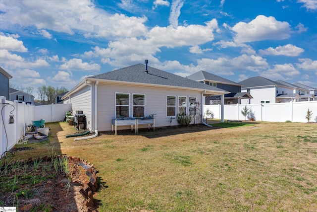 rear view of house featuring a lawn and a fenced backyard