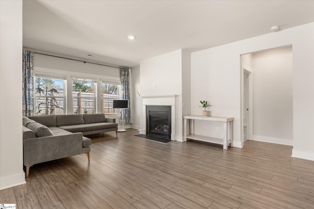 living room with a fireplace with flush hearth, baseboards, wood finished floors, and recessed lighting