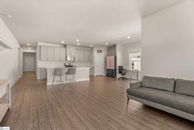 living area featuring baseboards, light wood-style floors, and recessed lighting