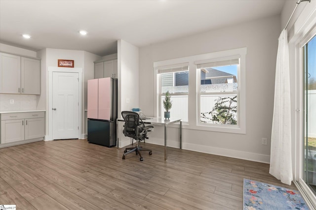 unfurnished office with baseboards, light wood-style flooring, and recessed lighting