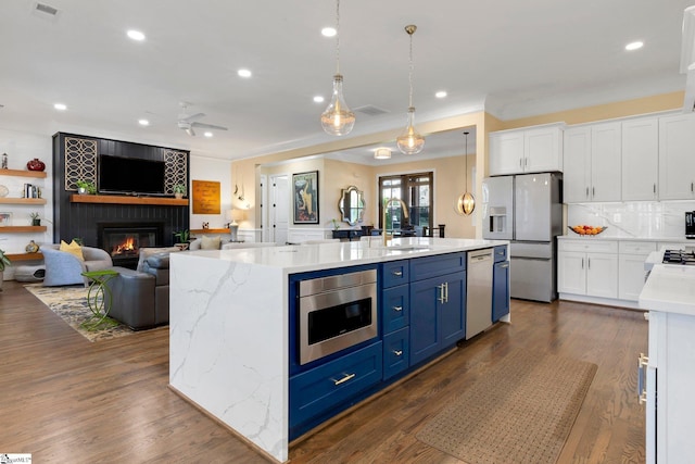 9 Graywood Ct, Simpsonville, SC 29680 - kitchen with a large fireplace, a sink, dark wood-style floors, white cabinets, and appliances with stainless steel finishes
