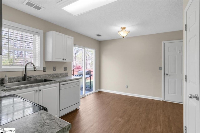 kitchen with dark wood-style flooring, white cabinets, visible vents, a sink, and white dishwasher