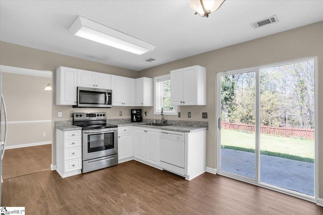 kitchen with visible vents, a sink, dark wood-style flooring, and appliances with stainless steel finishes