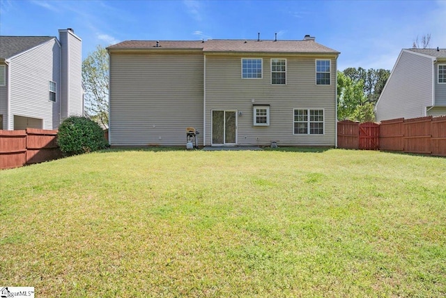 rear view of house with a fenced backyard and a lawn