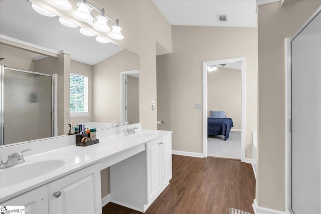 ensuite bathroom featuring a sink, visible vents, a stall shower, and wood finished floors