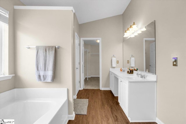 full bathroom featuring double vanity, a sink, a garden tub, and wood finished floors