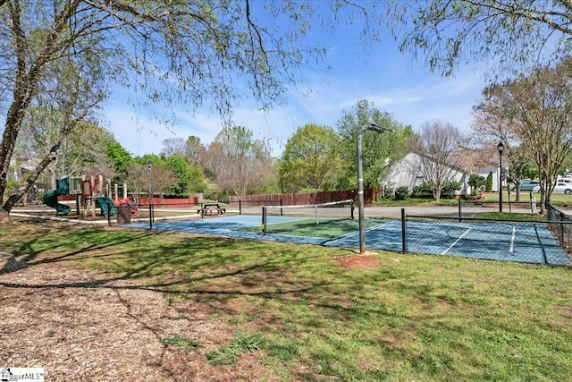 view of tennis court featuring fence, playground community, and a yard