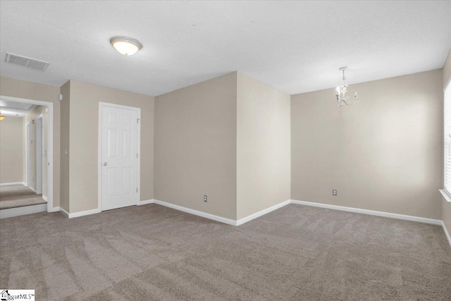 spare room featuring an inviting chandelier, carpet flooring, baseboards, and visible vents