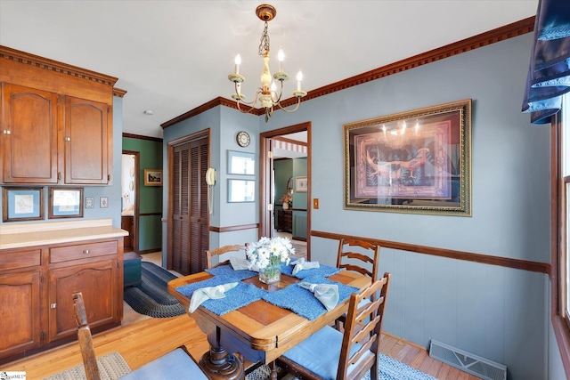 202 Mornington Ct, Simpsonville, SC 29681 - dining area with visible vents, light wood-style flooring, wainscoting, and an inviting chandelier