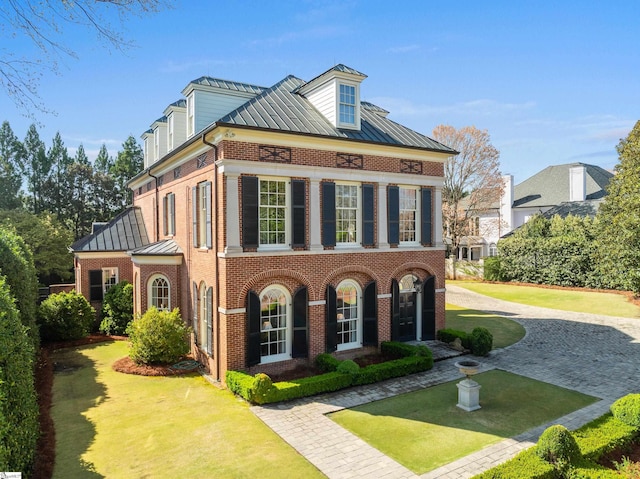 view of front of property featuring brick siding, a front yard, a standing seam roof, and metal roof