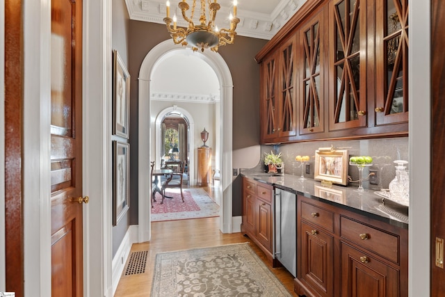 bar featuring light wood-style flooring, visible vents, a chandelier, crown molding, and backsplash