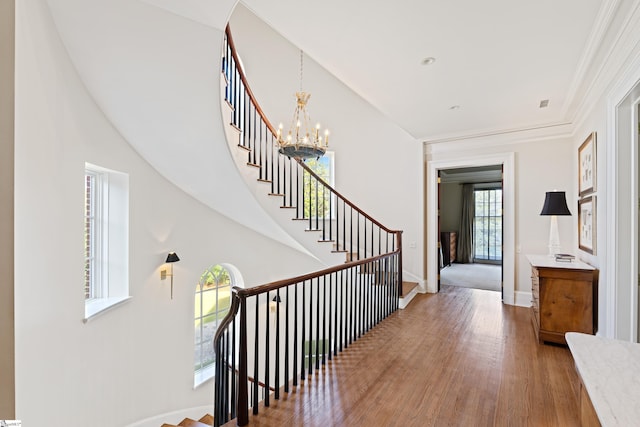 hallway with baseboards, stairs, wood finished floors, and an inviting chandelier