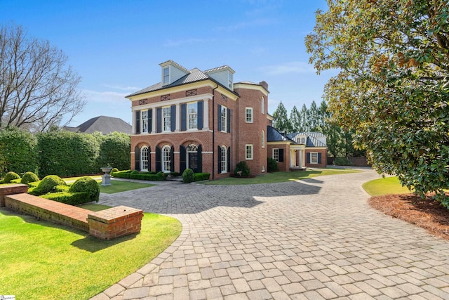 colonial-style house with a front yard, brick siding, and curved driveway