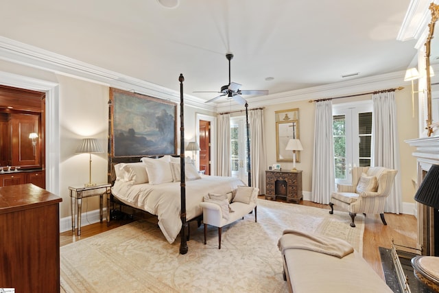 bedroom with ornamental molding, a fireplace, and wood finished floors