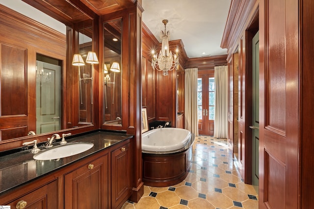 bathroom featuring ornamental molding, a jetted tub, an inviting chandelier, and vanity