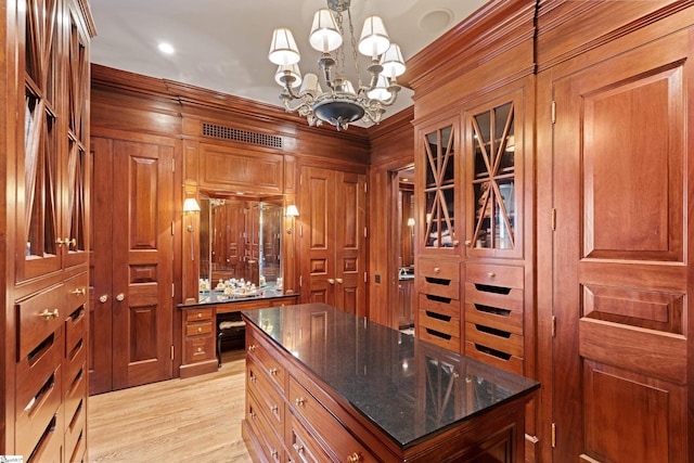 walk in closet with light wood-style flooring and an inviting chandelier