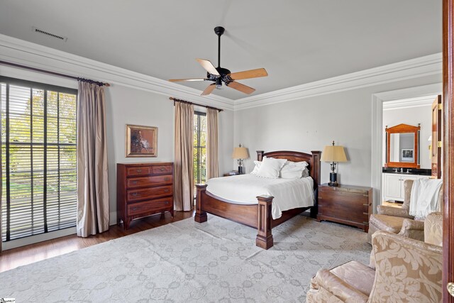 bedroom with a ceiling fan, wood finished floors, ornamental molding, and visible vents