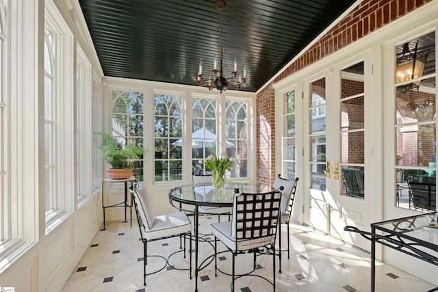 sunroom with a notable chandelier and brick wall