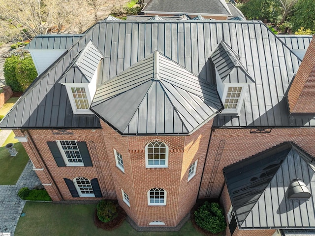 view of home's exterior featuring brick siding, a standing seam roof, and metal roof