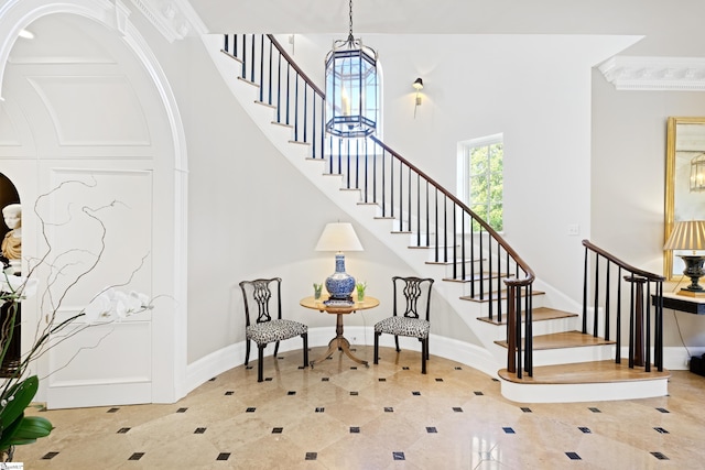 stairs featuring a high ceiling, crown molding, and baseboards