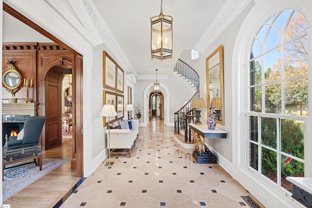 foyer entrance featuring ornamental molding, arched walkways, stairs, and visible vents