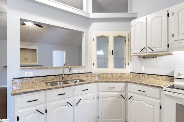 kitchen with a sink, white cabinetry, light stone countertops, white electric range, and ceiling fan