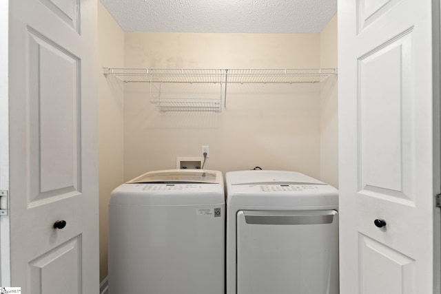 washroom featuring washing machine and dryer, laundry area, and a textured ceiling