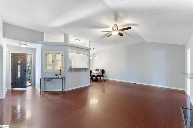 unfurnished living room with vaulted ceiling, ceiling fan with notable chandelier, baseboards, a textured ceiling, and wood finished floors