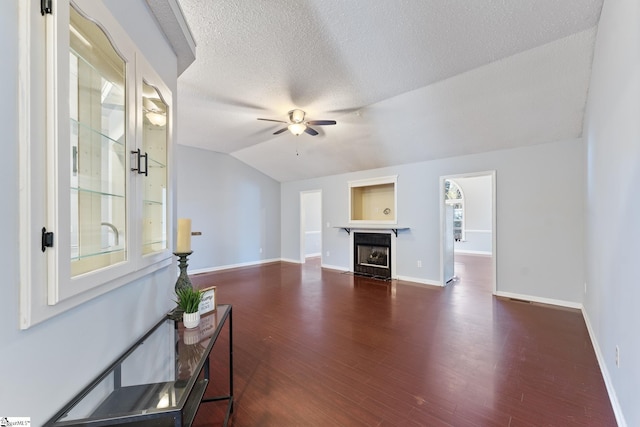 living room featuring a fireplace with flush hearth, lofted ceiling, dark wood-type flooring, and ceiling fan