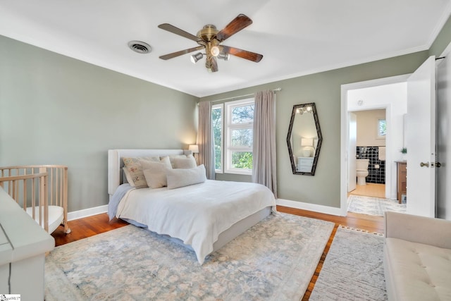 bedroom featuring wood finished floors, crown molding, baseboards, and visible vents