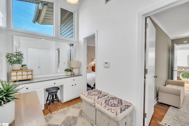 interior space with a high ceiling, crown molding, and light wood finished floors