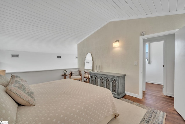 bedroom featuring wood finished floors, lofted ceiling, baseboards, visible vents, and ornamental molding