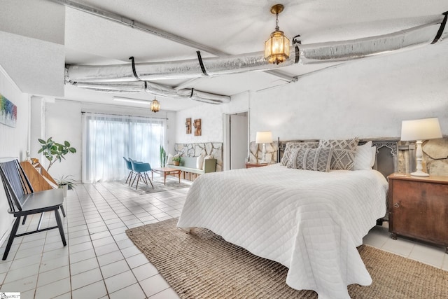 bedroom with access to outside, a textured ceiling, and light tile patterned floors