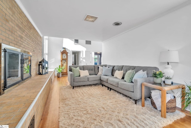 living room with visible vents, ornamental molding, and wood finished floors