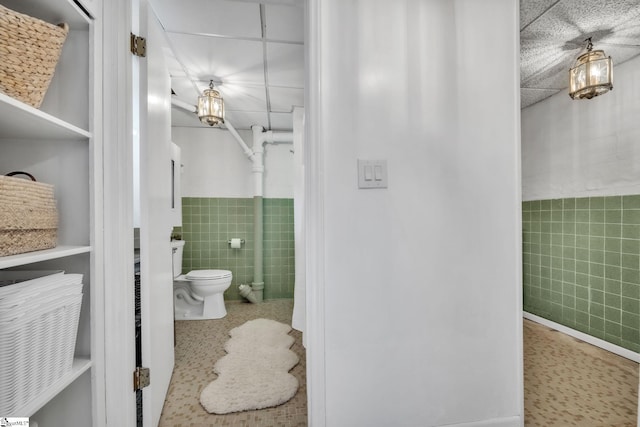 bathroom featuring toilet and tile walls