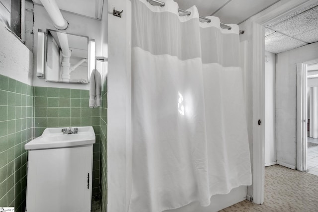 bathroom featuring tile walls, vanity, and curtained shower