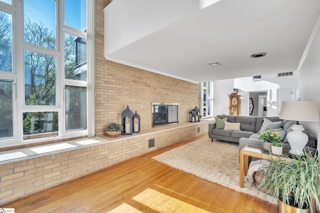 living room featuring wood finished floors, crown molding, a fireplace, and visible vents