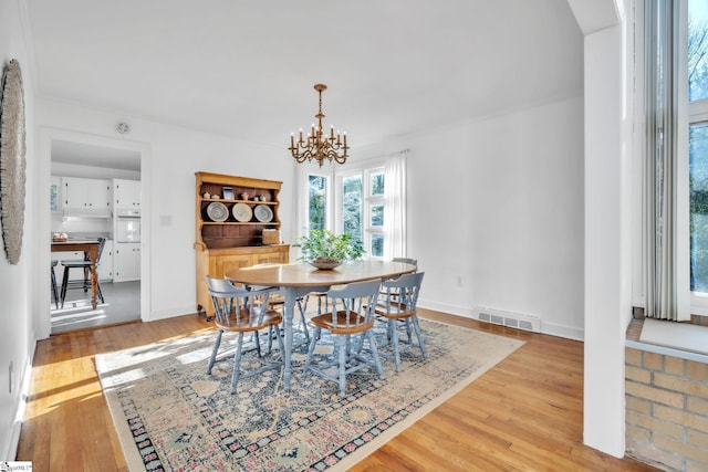 dining room with baseboards, visible vents, light wood-style flooring, and a chandelier